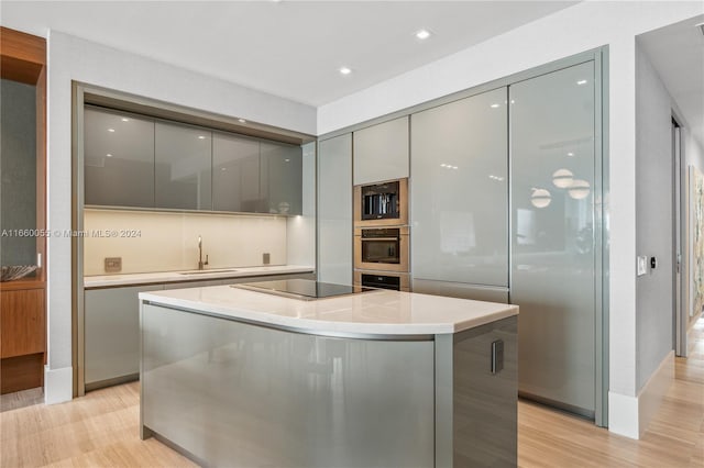 kitchen with gray cabinetry, a center island, black appliances, sink, and light wood-type flooring