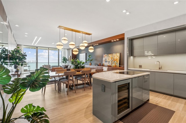 kitchen with hanging light fixtures, gray cabinets, and beverage cooler