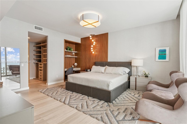 bedroom featuring a walk in closet, a closet, and light wood-type flooring