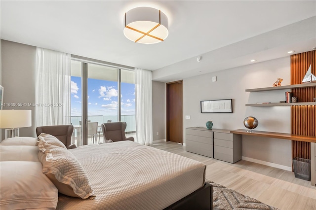 bedroom with access to outside, light hardwood / wood-style floors, and a wall of windows