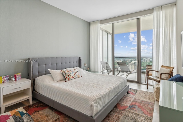 bedroom featuring access to outside, floor to ceiling windows, and wood-type flooring