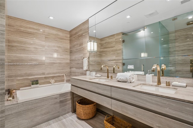 bathroom with vanity, tiled bath, and tile walls