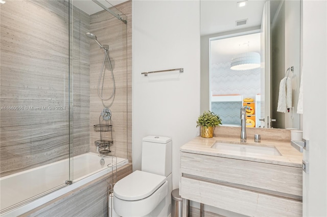 full bathroom featuring vanity, bath / shower combo with glass door, and toilet