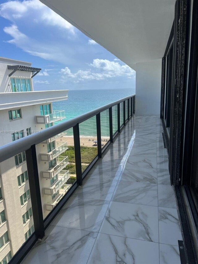 balcony featuring a water view and a beach view