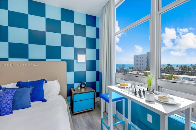 bedroom with light hardwood / wood-style flooring and a water view