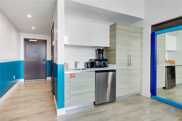 kitchen with white cabinets, sink, light hardwood / wood-style floors, and stainless steel dishwasher