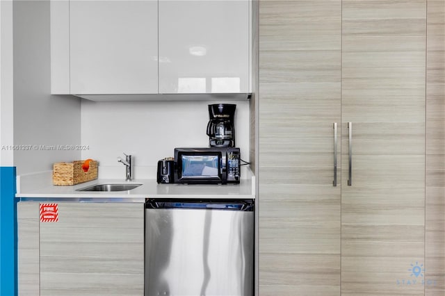 kitchen featuring dishwasher, sink, and white cabinetry