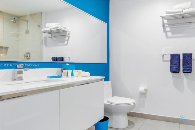 bathroom featuring a tile shower, tile patterned flooring, vanity, and toilet