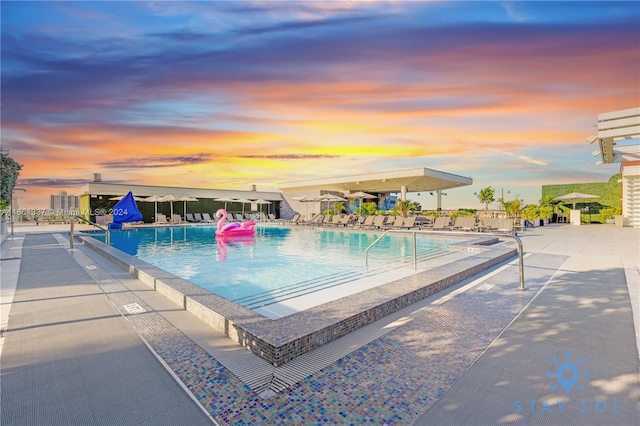 pool at dusk with a patio area