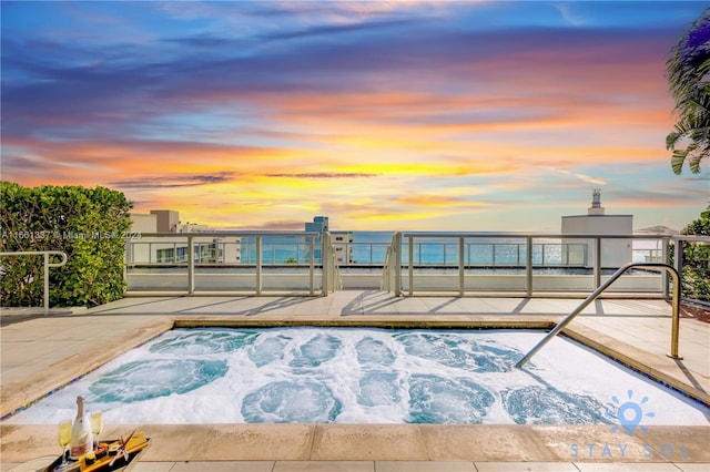 pool at dusk with an in ground hot tub