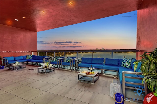 patio terrace at dusk featuring a water view and outdoor lounge area