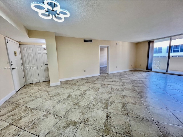 spare room featuring a chandelier and a textured ceiling