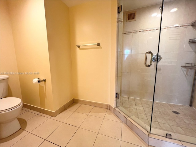 bathroom with tile patterned flooring, toilet, and an enclosed shower