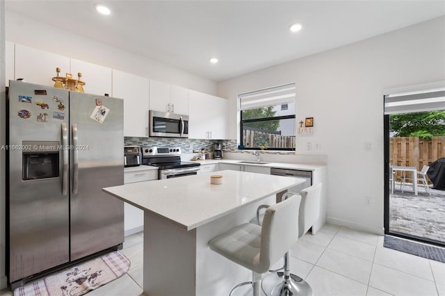 kitchen with white cabinets, sink, a kitchen island, stainless steel appliances, and a kitchen breakfast bar