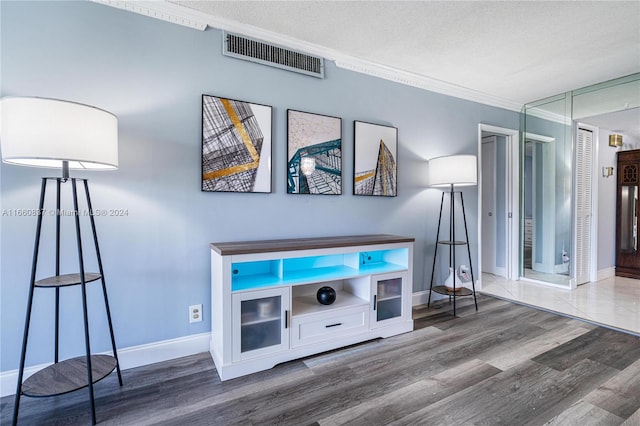 interior space featuring ornamental molding, a textured ceiling, and hardwood / wood-style flooring