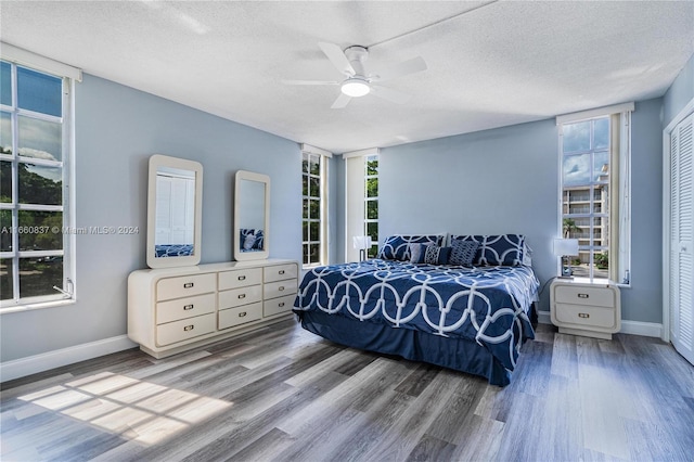 bedroom with ceiling fan, a textured ceiling, hardwood / wood-style floors, and multiple windows