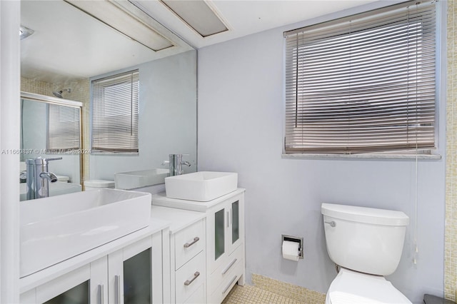 bathroom with a wealth of natural light, a shower with shower door, vanity, and toilet