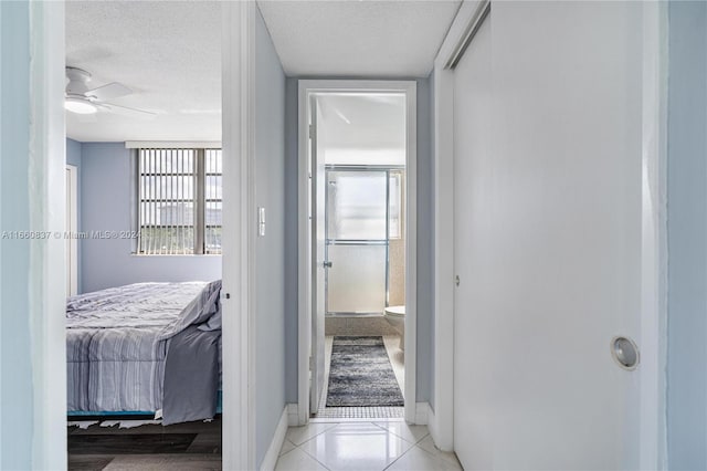 hallway with a textured ceiling and light tile patterned floors