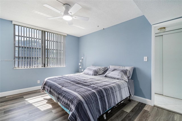 bedroom featuring ceiling fan, dark hardwood / wood-style floors, and a textured ceiling