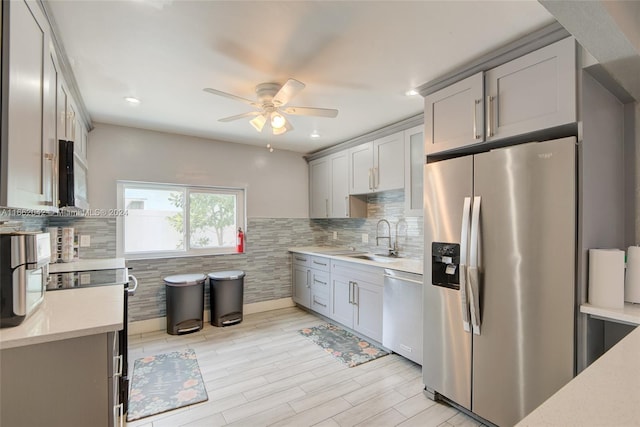 kitchen with ceiling fan, sink, gray cabinets, stainless steel appliances, and decorative backsplash