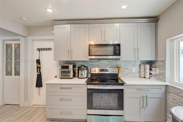 kitchen featuring stainless steel appliances, light hardwood / wood-style floors, and tasteful backsplash