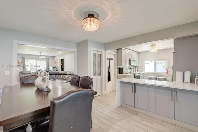 dining space featuring ceiling fan with notable chandelier, light hardwood / wood-style floors, and plenty of natural light