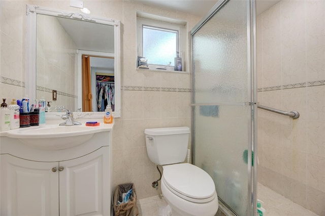 bathroom featuring vanity, tile walls, toilet, and a shower with door