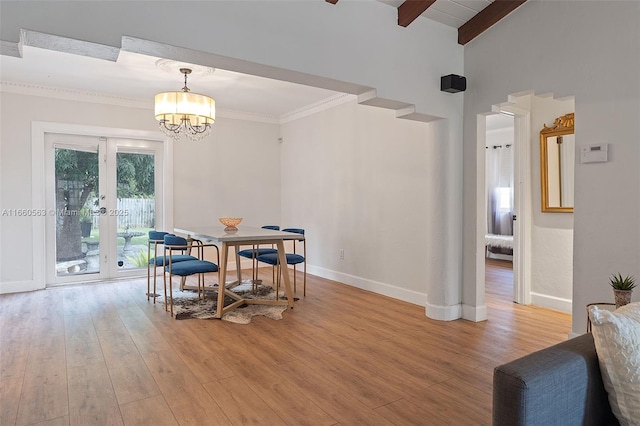 dining room featuring an inviting chandelier, lofted ceiling with beams, ornamental molding, french doors, and light wood-type flooring