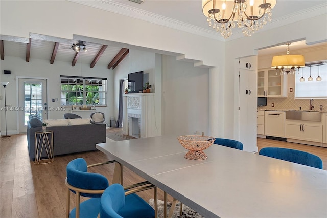 dining space with beamed ceiling, sink, hardwood / wood-style flooring, ornamental molding, and a notable chandelier