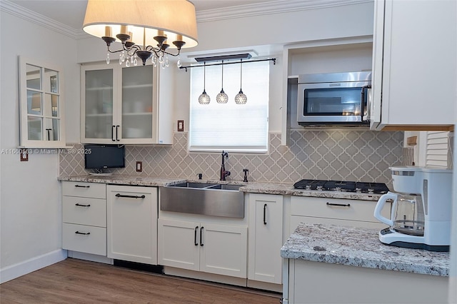 kitchen with sink, white cabinetry, ornamental molding, pendant lighting, and stainless steel appliances