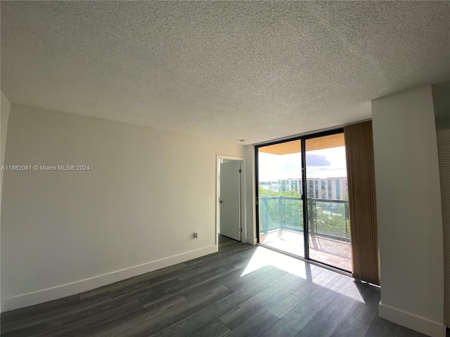 empty room featuring a textured ceiling, dark hardwood / wood-style floors, and a wall of windows