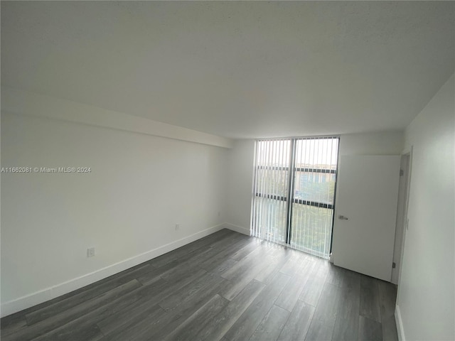 unfurnished room featuring floor to ceiling windows and dark wood-type flooring