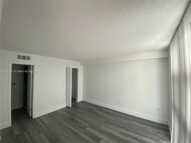 unfurnished bedroom featuring a textured ceiling and dark hardwood / wood-style flooring