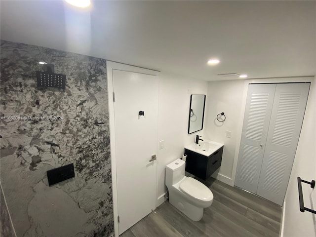 bathroom with a shower, wood-type flooring, vanity, and toilet