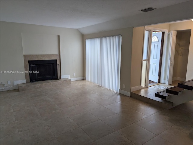 unfurnished living room featuring light tile patterned flooring, a fireplace, and lofted ceiling