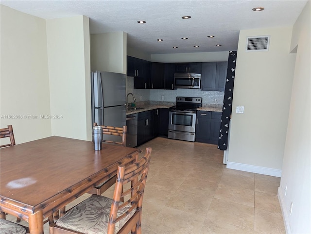 kitchen featuring light stone counters, light tile patterned flooring, sink, stainless steel appliances, and decorative backsplash