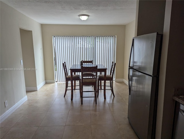 dining area with a textured ceiling and light tile patterned floors