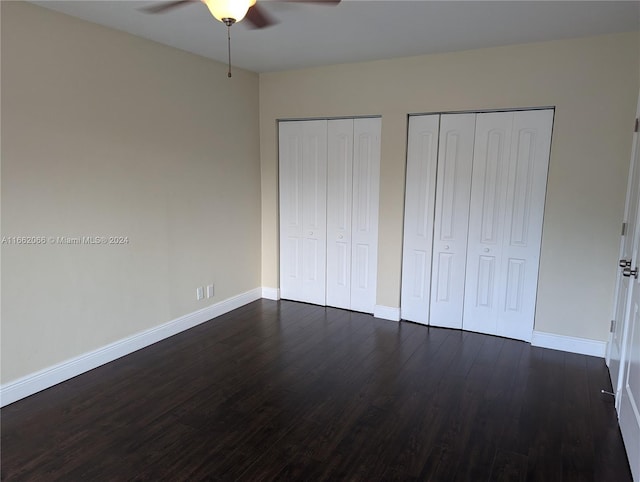 unfurnished bedroom featuring ceiling fan, two closets, and dark hardwood / wood-style floors