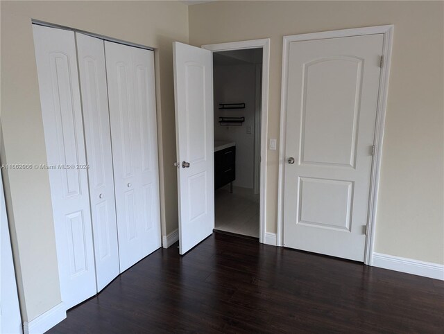 unfurnished bedroom with a closet and dark hardwood / wood-style floors