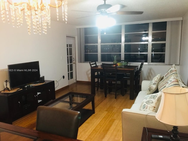 living room featuring wood-type flooring and ceiling fan with notable chandelier