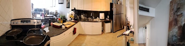 kitchen featuring stainless steel refrigerator and white cabinets