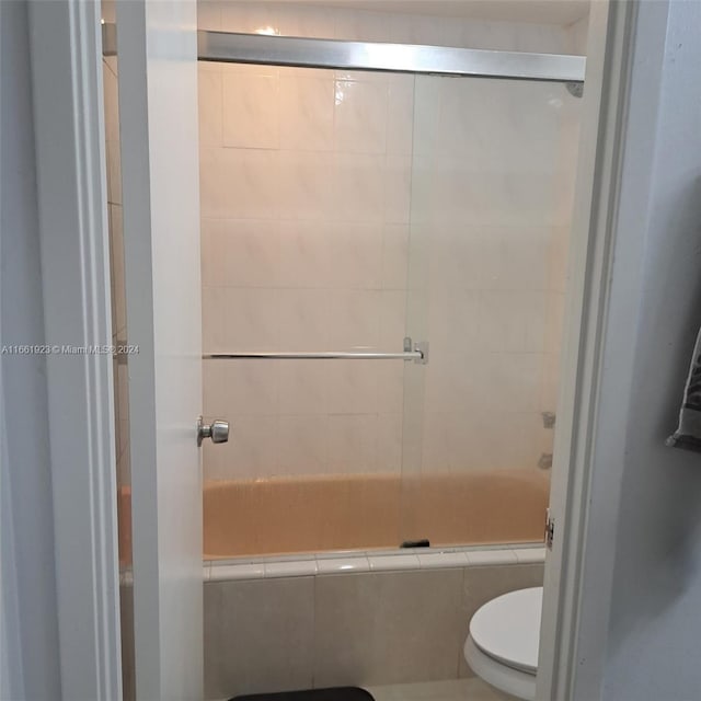 bathroom with combined bath / shower with glass door and toilet