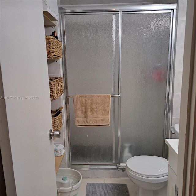 bathroom featuring tile patterned flooring, a shower with shower door, vanity, and toilet