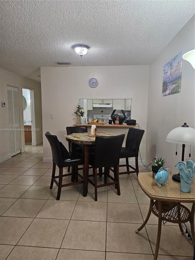 dining area featuring light tile patterned floors and a textured ceiling