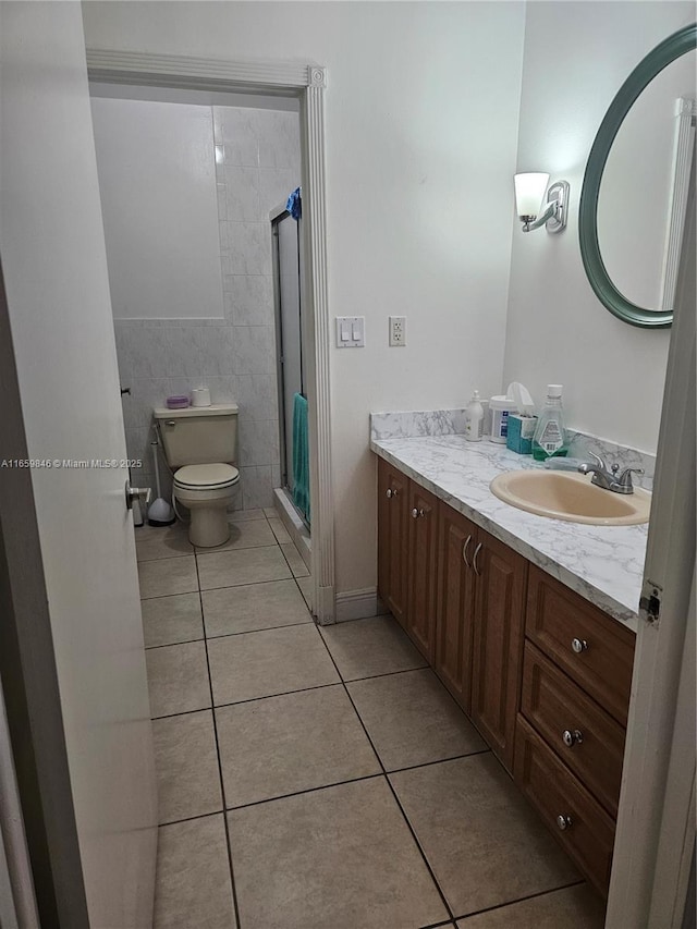 bathroom with vanity, toilet, an enclosed shower, and tile patterned flooring