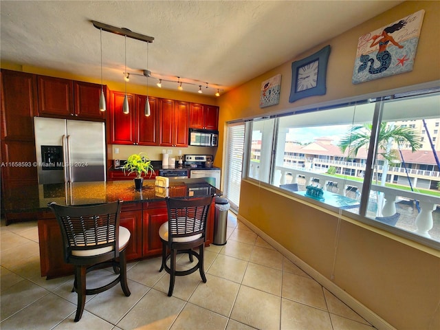 kitchen featuring pendant lighting, appliances with stainless steel finishes, a healthy amount of sunlight, and dark stone counters