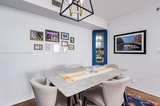 dining space with a notable chandelier, wood-type flooring, and crown molding