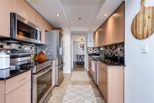 kitchen featuring dark stone counters, decorative backsplash, appliances with stainless steel finishes, and light brown cabinetry