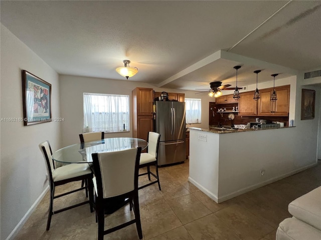 tiled dining area with a textured ceiling, a healthy amount of sunlight, and ceiling fan