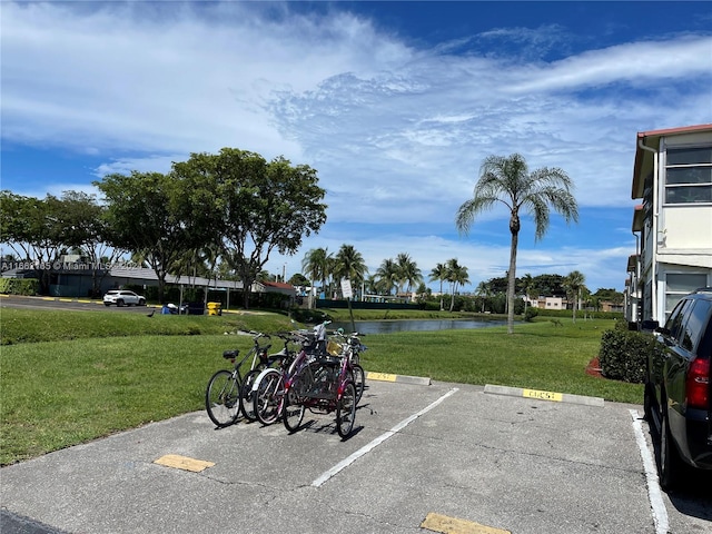 view of parking / parking lot featuring a yard and a water view